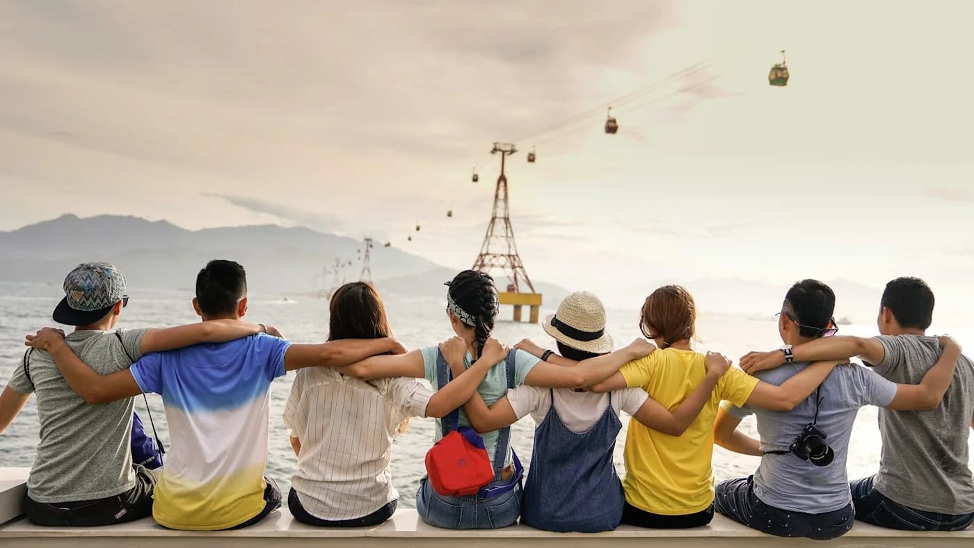 Friends sitting shoulder to shoulder by the water