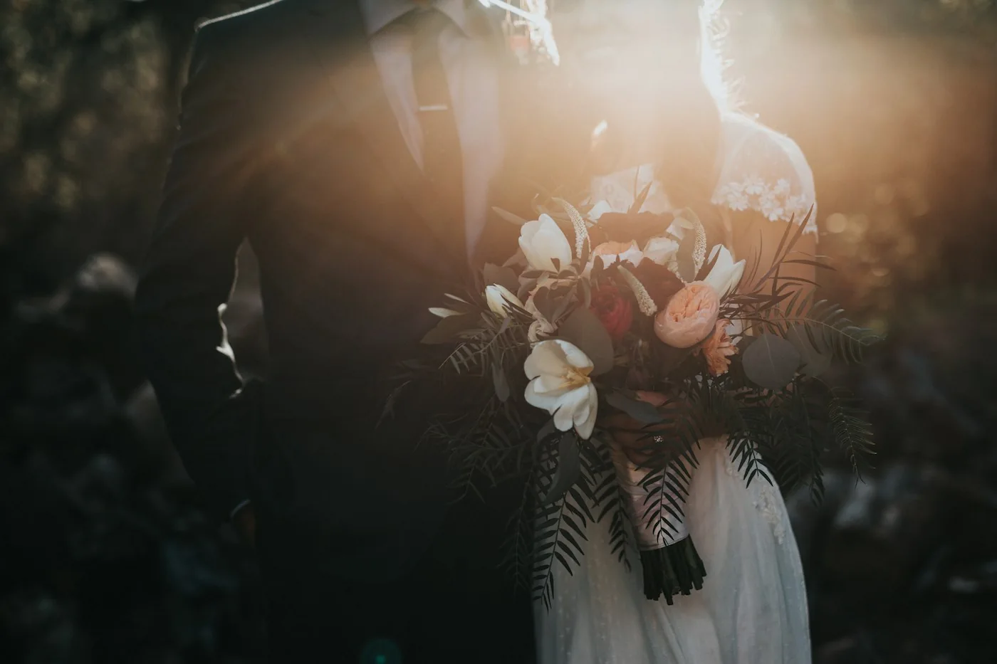 A wedding couple holding a bouquet in warm evening light